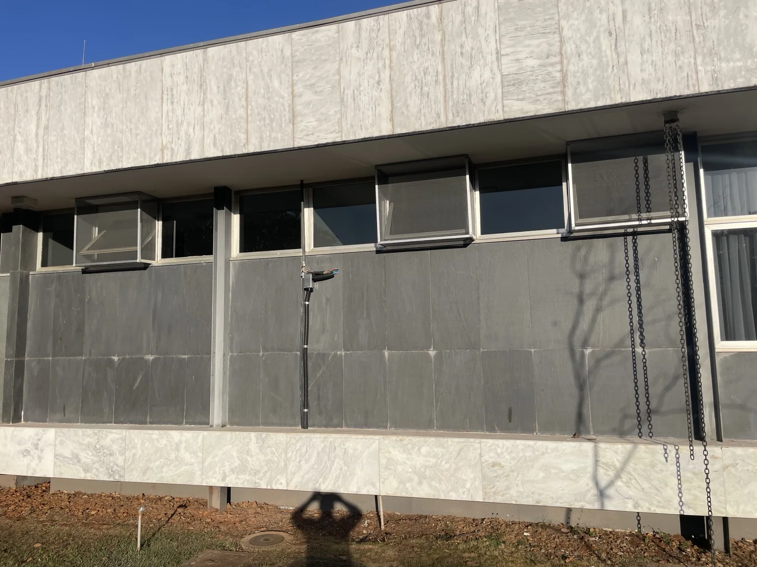 Janelas com telas mosquiteiras junto aos vãos superiores da fachada