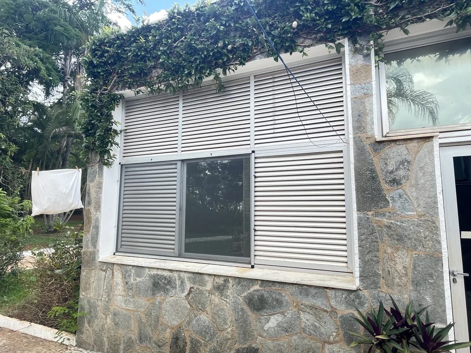 Tela mosquiteira com perfil natural em janela de fachada revestida em pedra