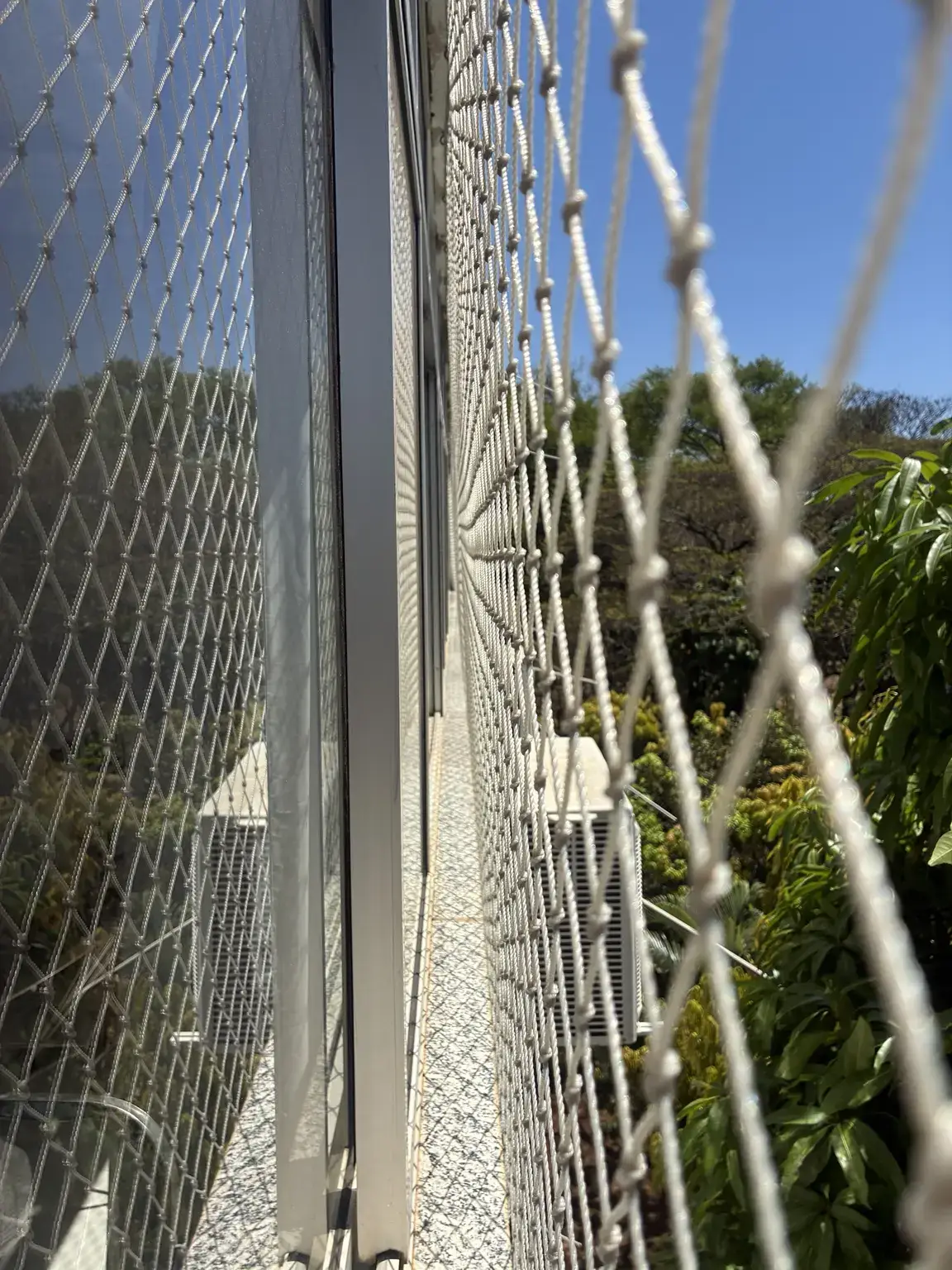Detalhe lateral da rede de proteção 5×5 cm na cor areia junto à esquadria da SQS 306