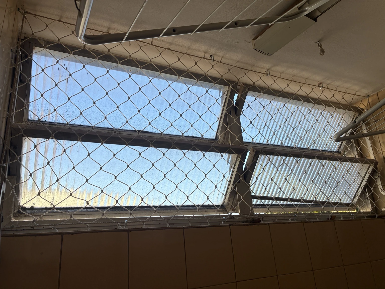 Rede de proteção areia 5×5 cm na janela da área de serviço, junto ao varal, na SQS 414, Bloco E