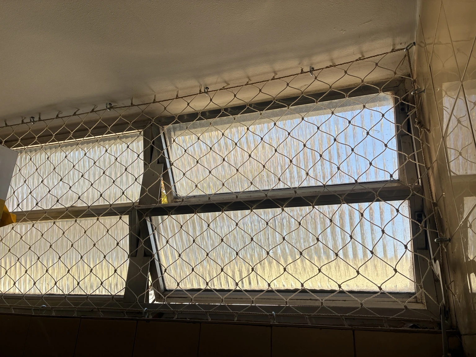 Detalhe da rede 5×5 cm na cor areia e dos pontos de fixação na janela da SQS 414, Bloco E, Asa Sul