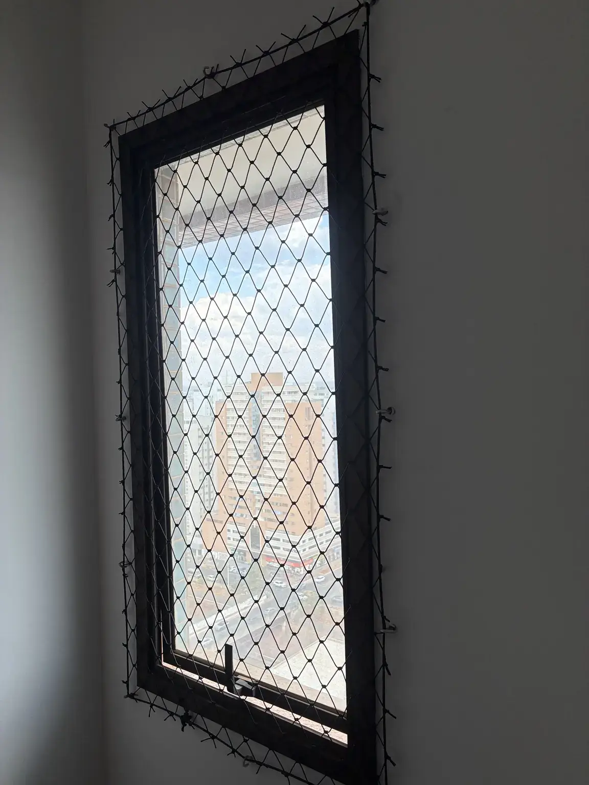 Rede de proteção preta instalada em janela vertical estreita no Edifício Mirante das Águas