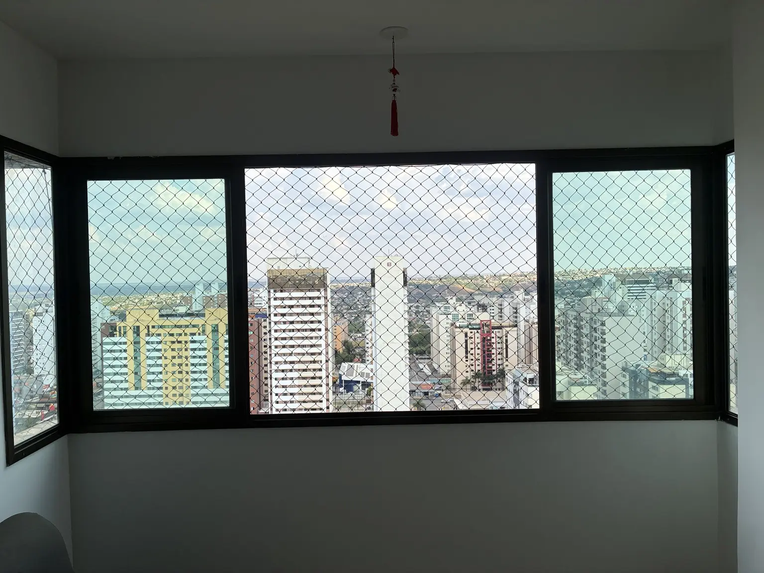 Conjunto de janelas em ângulo protegido com rede preta no Edifício Mirante das Águas