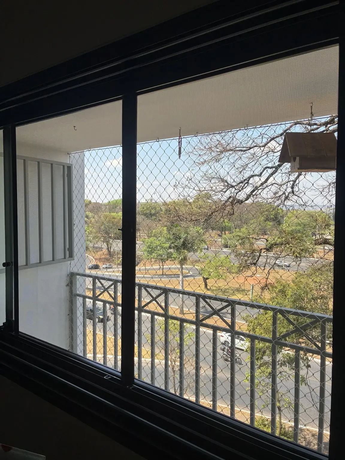 Detalhe lateral da tela mosquiteira preta e da rede de proteção.