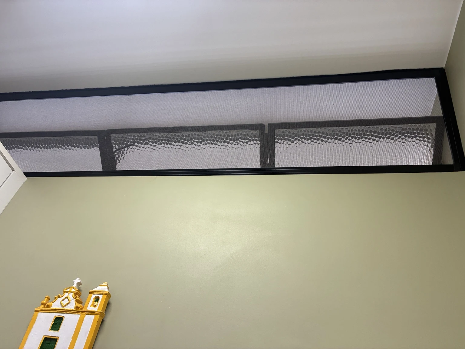 Tela mosquiteira preta instalada no vão superior da janela.