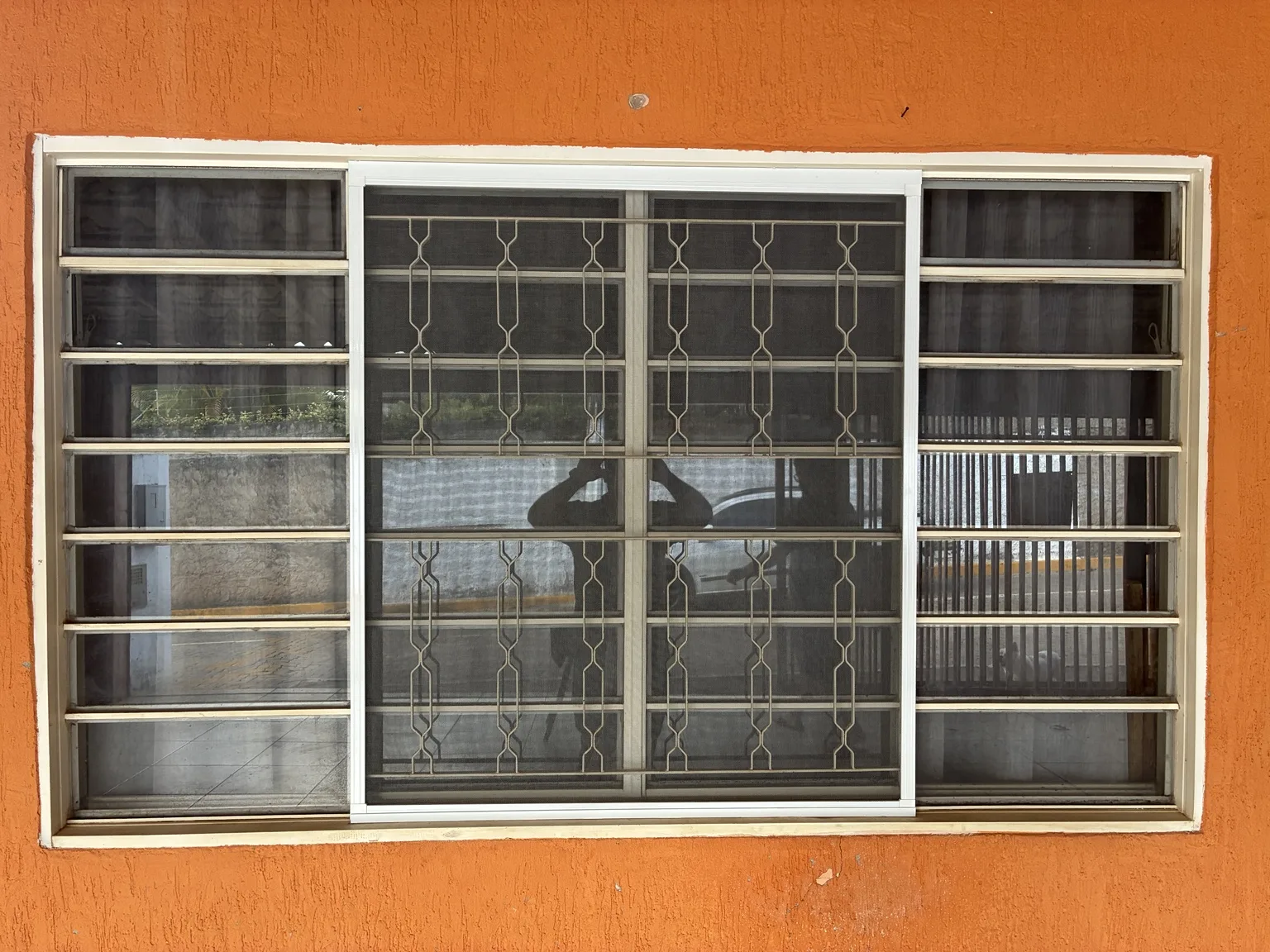 Tela mosquiteira branca na janela da fachada laranja — Chácara 23A, Colônia Agrícola Águas Claras.