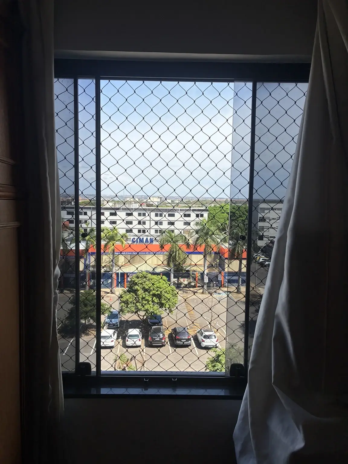 Vista frontal da rede de proteção junto às esquadrias escuras do apartamento.