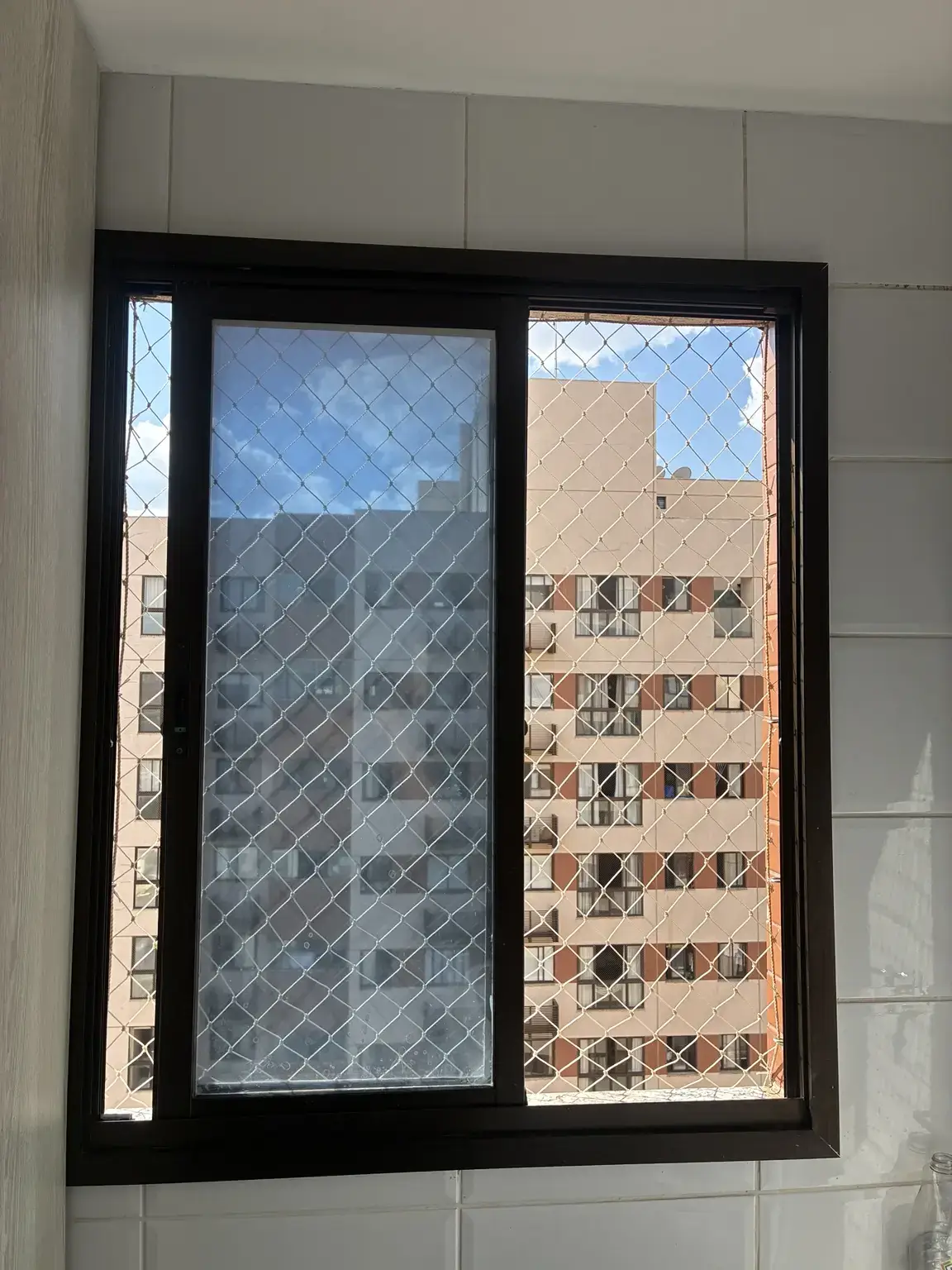 Rede de proteção 5×5 cm na cor areia instalada em janela do Edifício Dolce Vitta no Guará II, Brasília