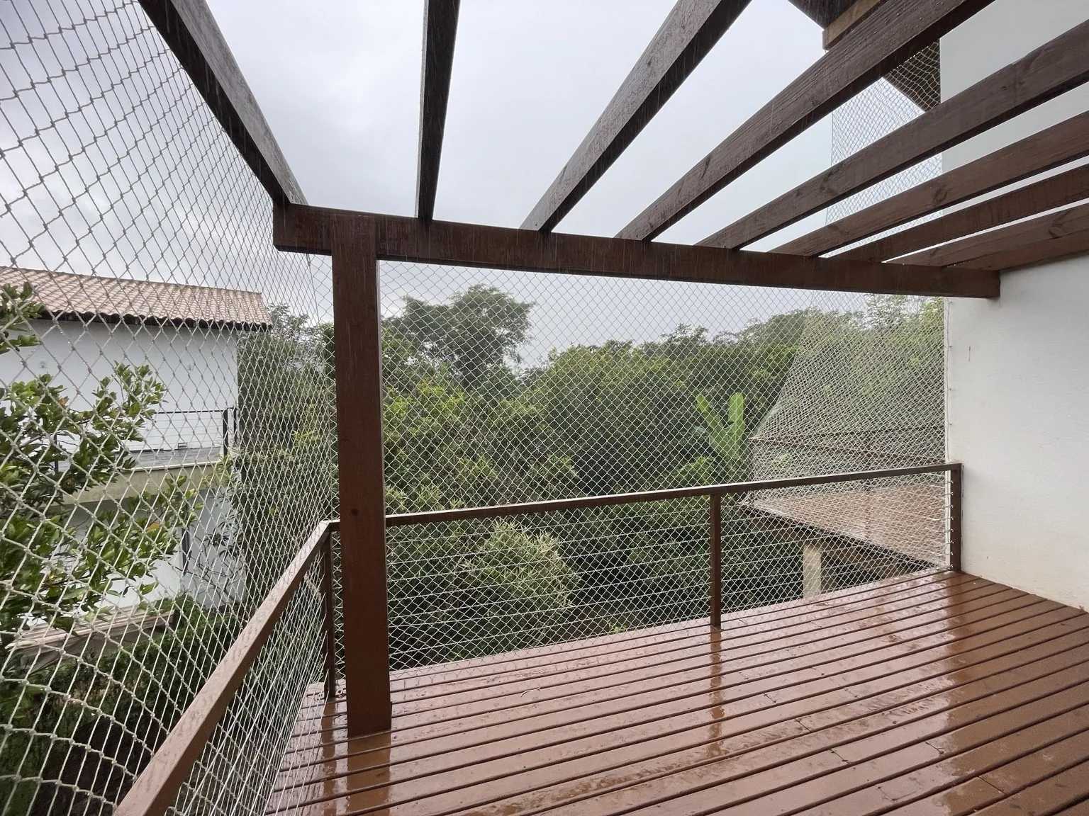 Rede areia instalada nas laterais da varanda com estrutura de madeira