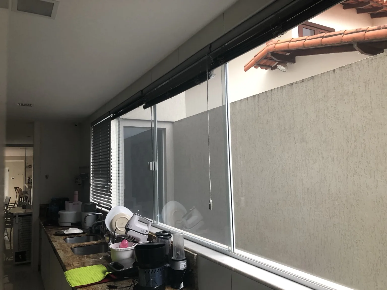 Janela da cozinha com tela mosquiteira branca junto à esquadria de correr