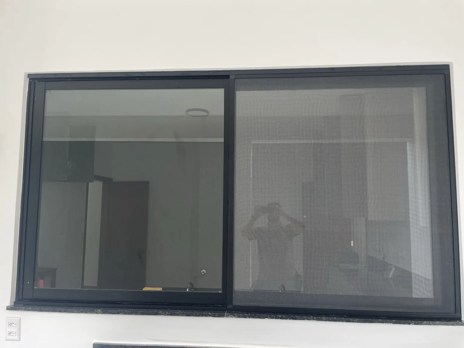 Tela mosquiteira preta instalada em janela vista pelo lado interno