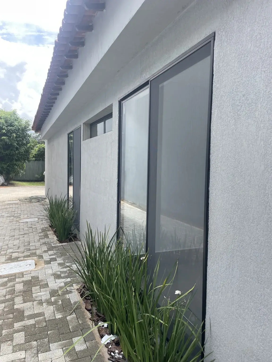 Porta de correr com tela mosquiteira preta ao lado de corredor externo