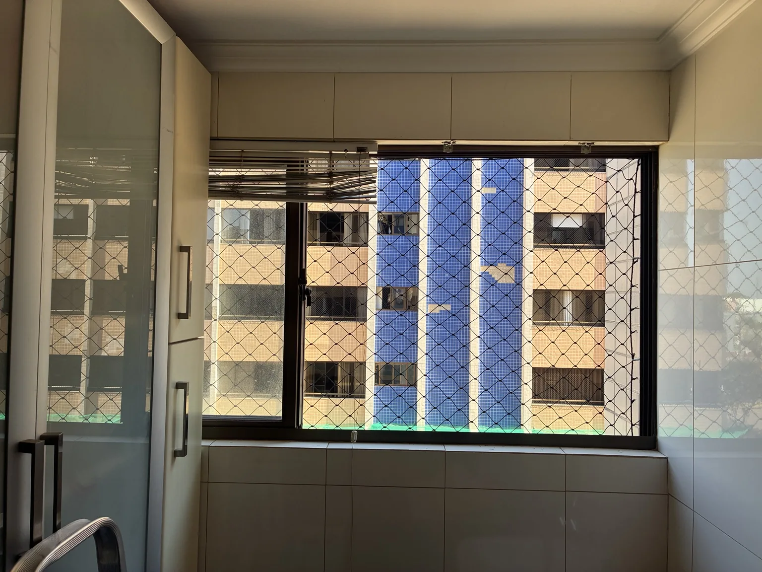 Rede preta em janela próxima à área de serviço do apartamento