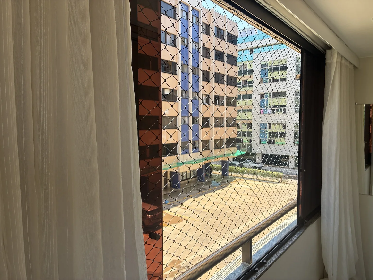 Detalhe lateral da rede de proteção preta junto à esquadria da janela