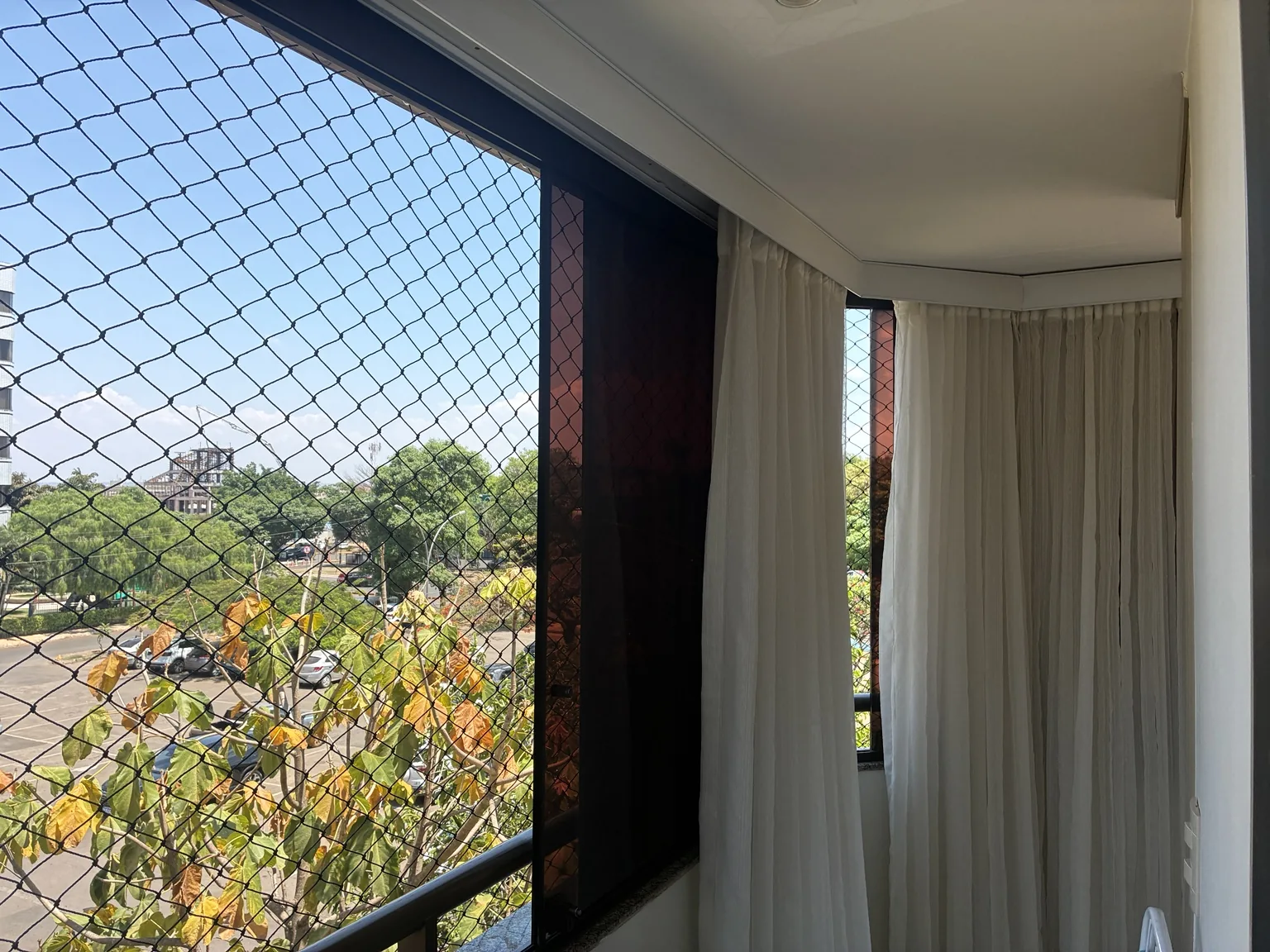 Rede preta 5×5 cm em janela com vista para árvores no Sudoeste