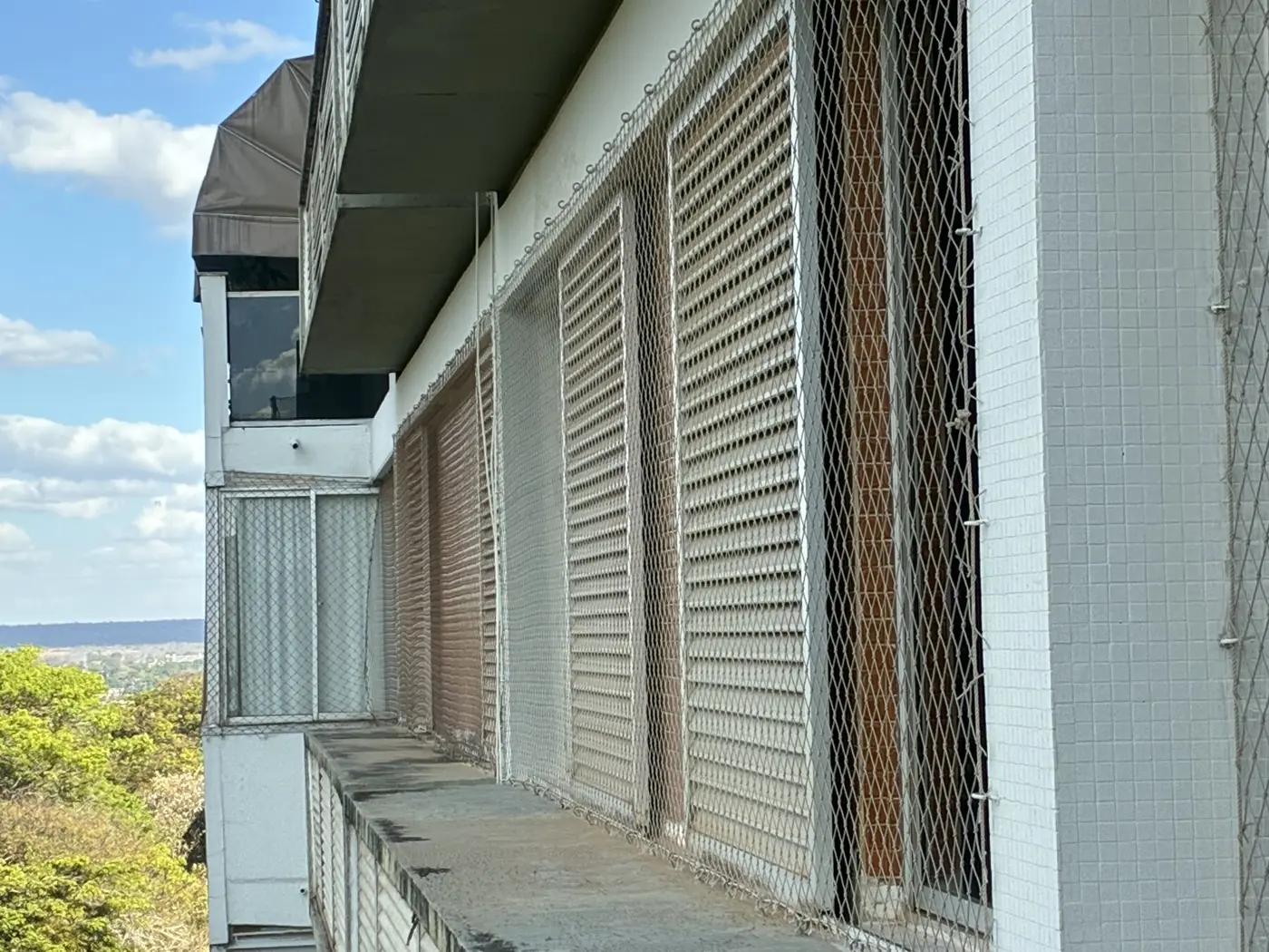 Fachada de edifício residencial com redes de proteção nas janelas na Asa Sul